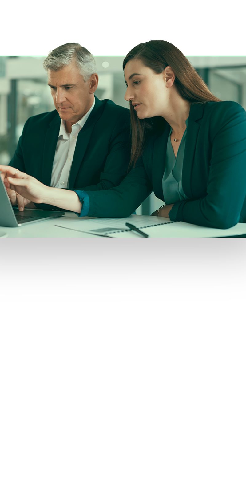 Two executives reviewing work together on a laptop