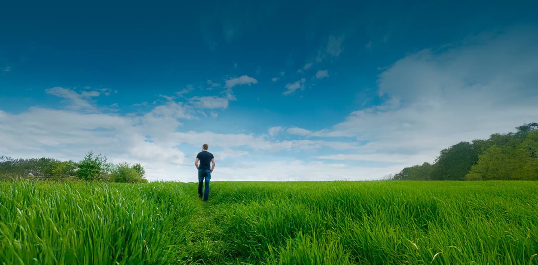 A professional walking through a green field under a blue sky