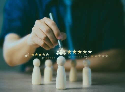 Hand placing wooden figures next to rating stars