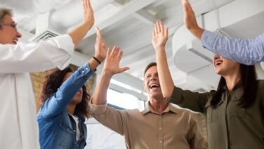 Empleados felices en oficina moderna como parte del salario emocional bajo la NOM-035, promoviendo bienestar laboral en M&eacute;xico &ndash; Kilpatrick