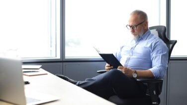 Dirigente seduto mentre legge un libro, simbolo di riflessione, pensiero strategico e leadership sostenibile.
