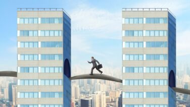 Líder empresarial cruzando un puente entre dos edificios de oficinas, como símbolo del liderazgo y el camino hacia el crecimiento futuro.